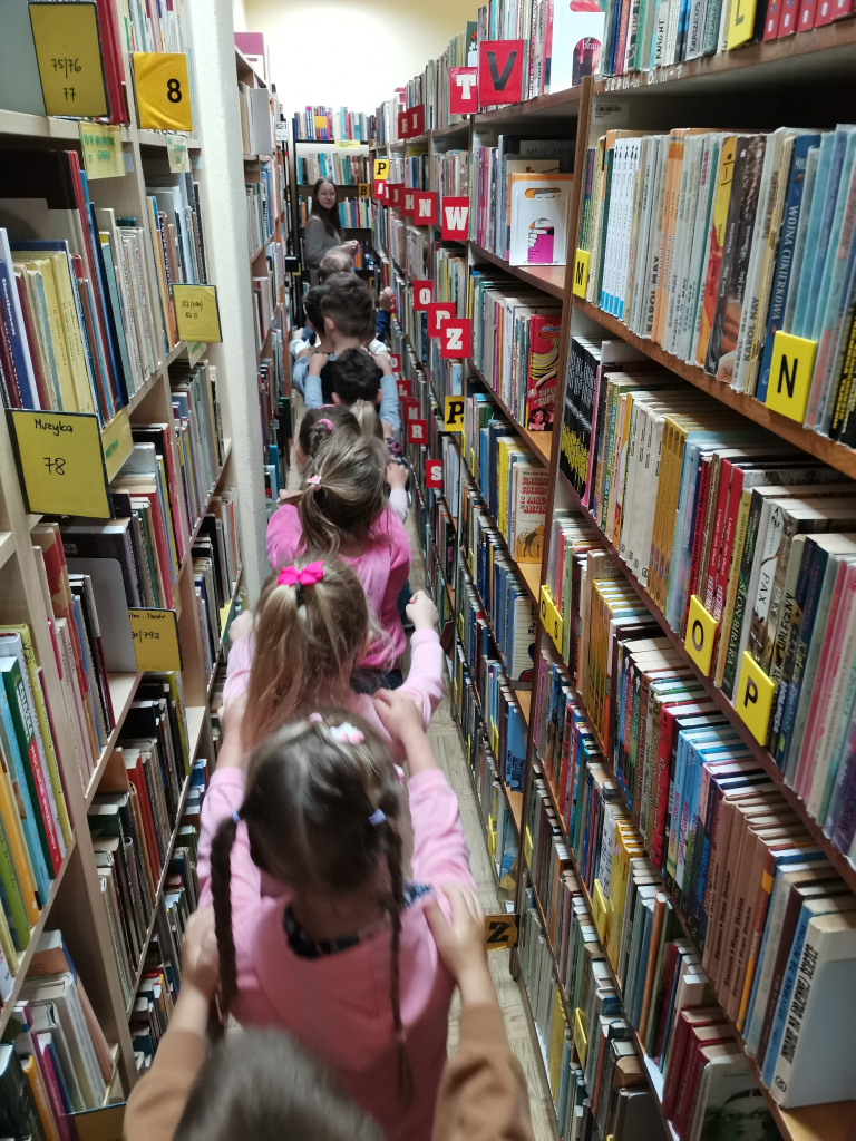 Pięciolatki zwiedzające bibliotekę bawiące się w zabawę Wesoły pociąg