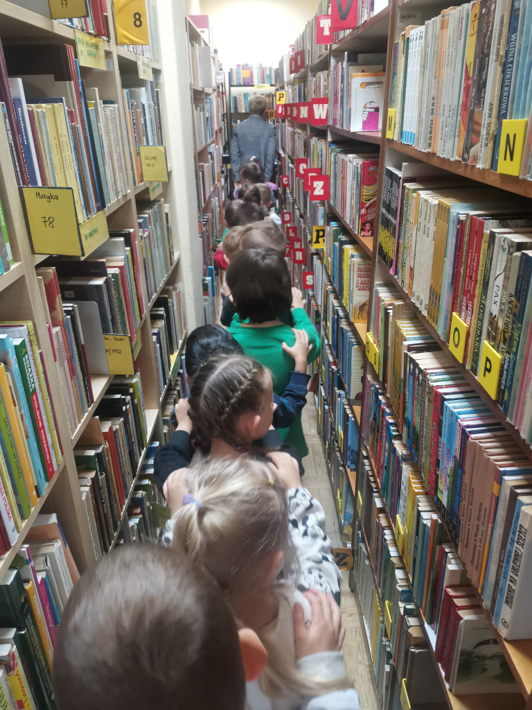 Przedszkolaki zwiedzające bibliotekę bawiące się w zabawę Wesoły pociąg