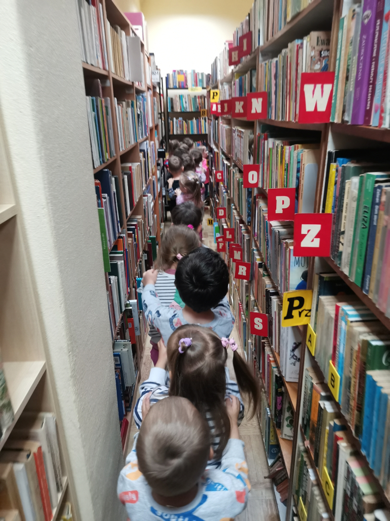 Przedszkolaki zwiedzające bibliotekę bawiące się w zabawę Wesoły pociąg