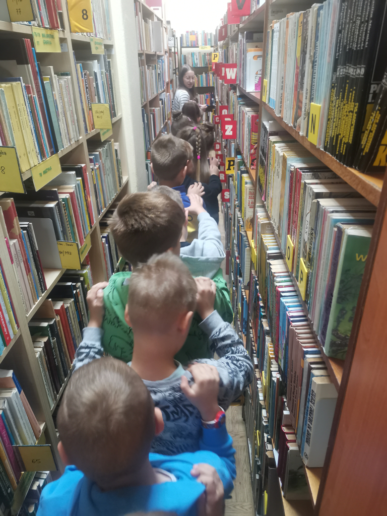 Sześciolatki zwiedzające bibliotekę bawiące się w zabawę Wesoły pociąg