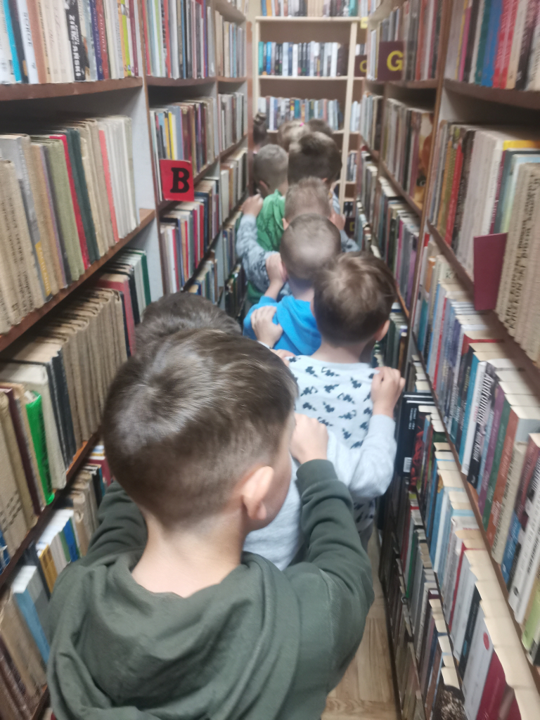 Przedszkolaki zwiedzające bibliotekę bawiące się w zabawę Wesoły pociąg