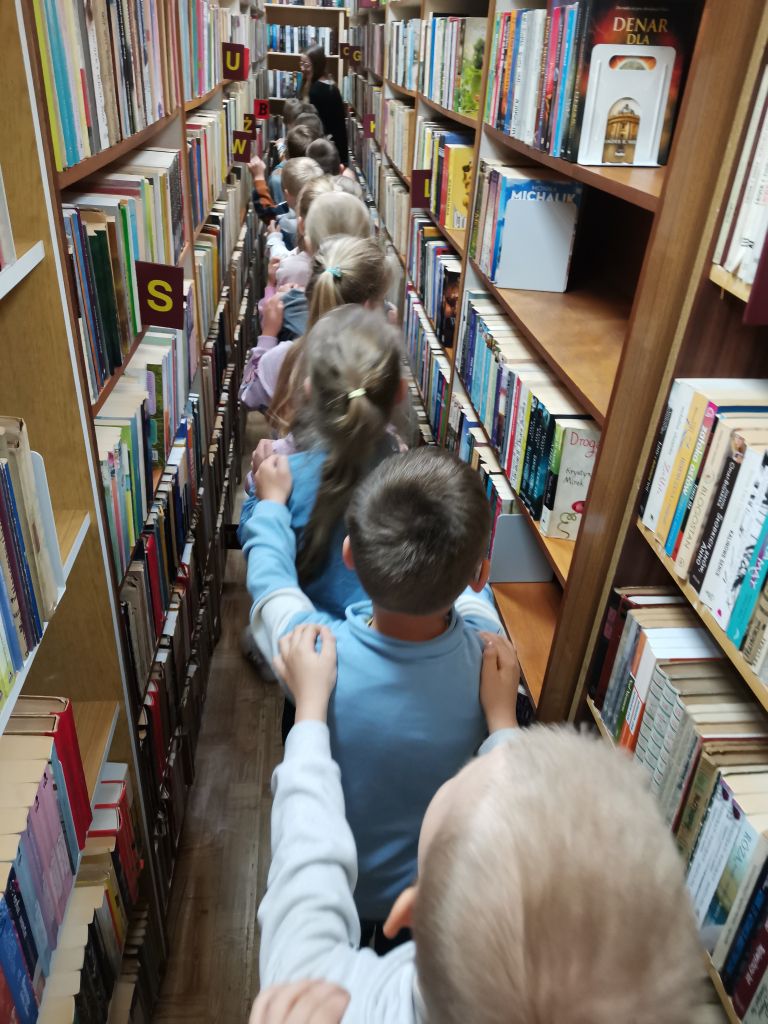 Przedszkolaki zwiedzające bibliotekę bawiące się w zabawę Wesoły pociąg