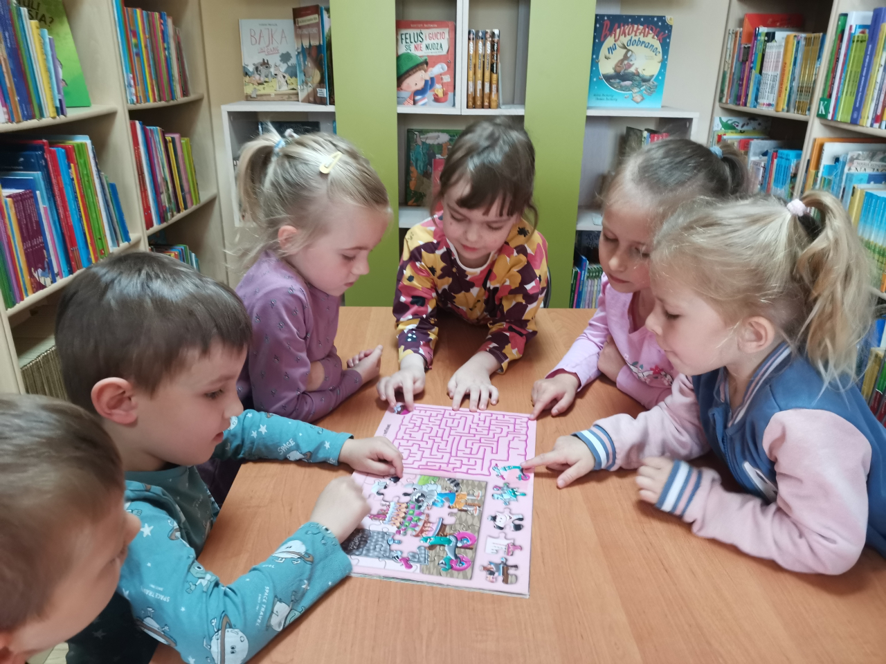 Dzieci rozwiązujące łamigłówki z czytanej książki W cukierni z cyklu Hulajnoga Zuzia